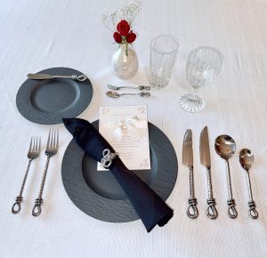 Close-up of Taos Twist handcrafted fork and spoon set arranged with wedding china and candles.